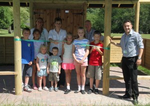 OPEN: Delph Primary school head teacher Alison Leigh and pupils cut the ribbon to open their new play complex with help from Groundwork Trust staff Ian Mansfield, Vicky Davenport, and Lee Watts of United Utilities. (Photo by Carl Royle)